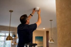Hands installing smoke detector on ceiling