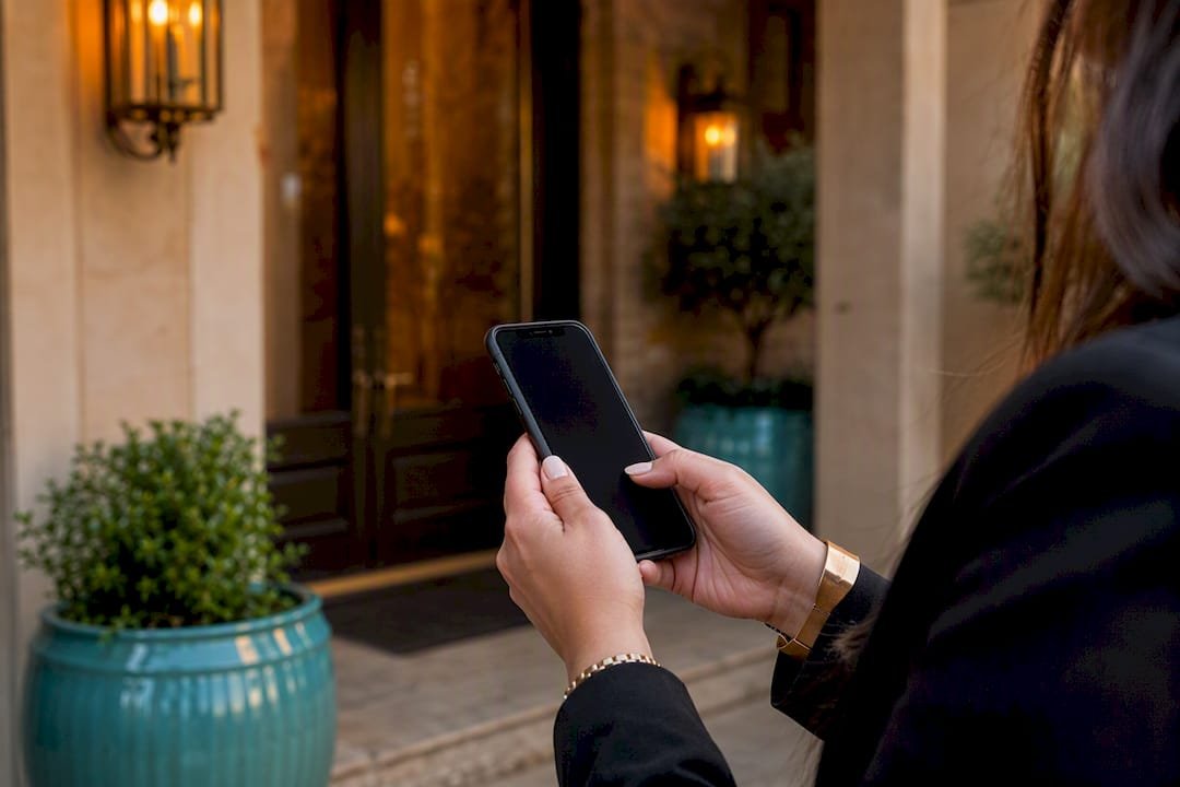 Agent texting on smartphone by home entrance